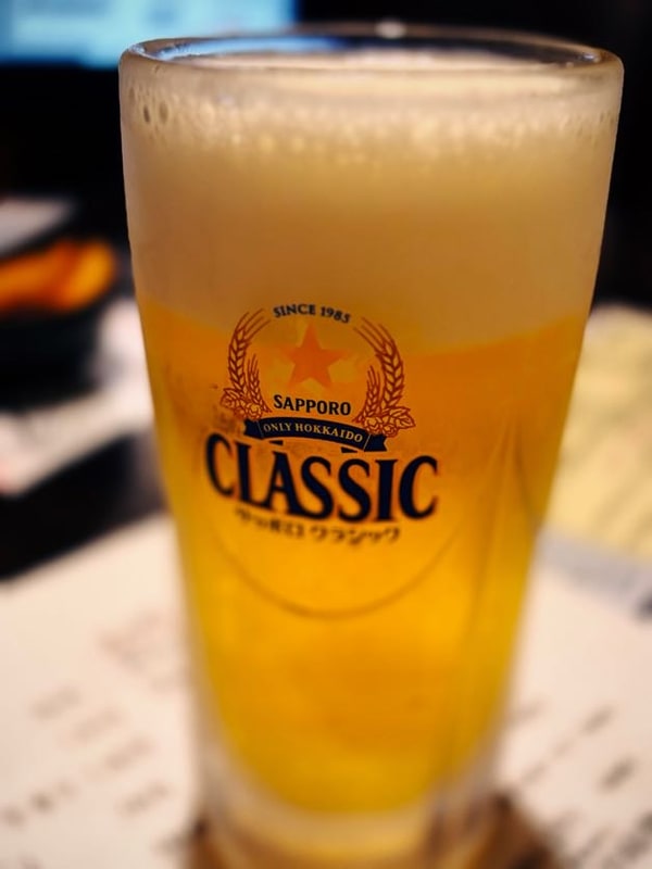 木の卓に置かれた、泡の立ったビールのグラス。