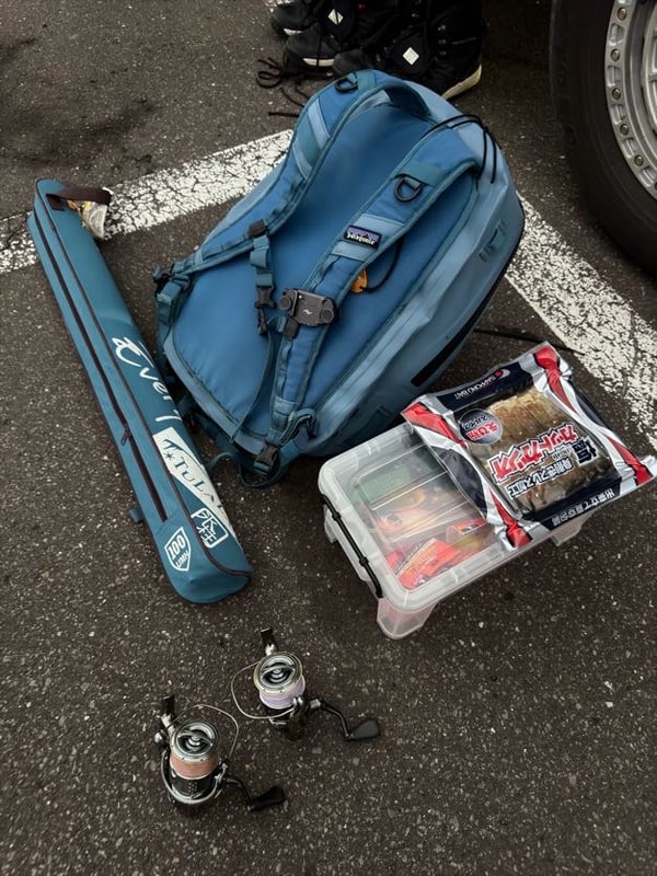 夜明け前の暗い舗装の上に、青い竿袋と道具箱と額に巻く明かりが並べてある。
