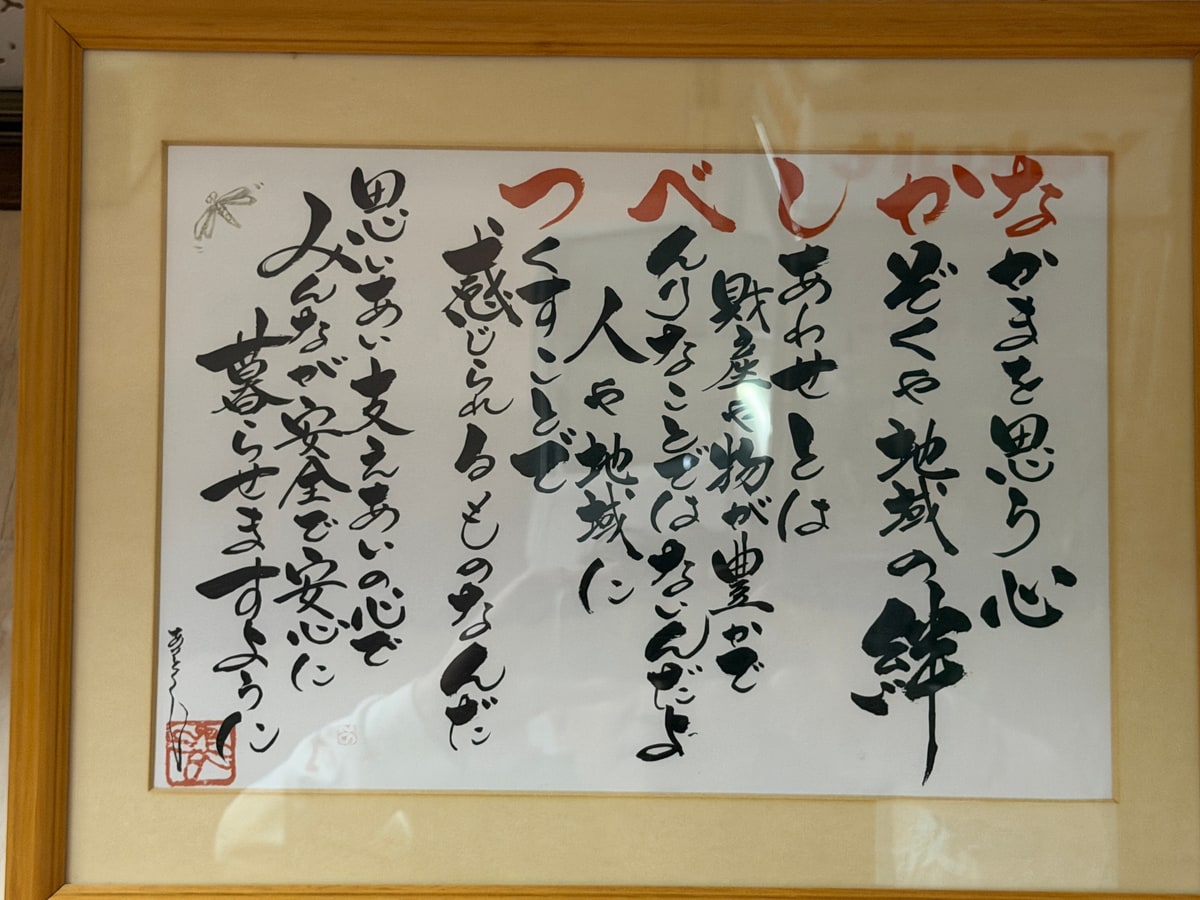 壁に掛けられた額の中に筆で書いた詩。各行の最初の一字だけが朱で書かれている。