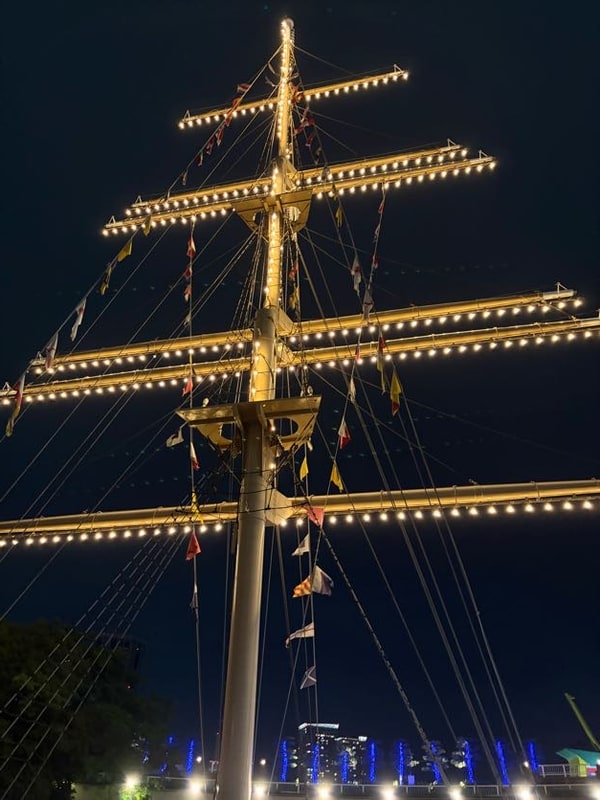 夜の空に、電球を並べた白いマストが立ち、横木から色とりどりの信号旗が下がっている。