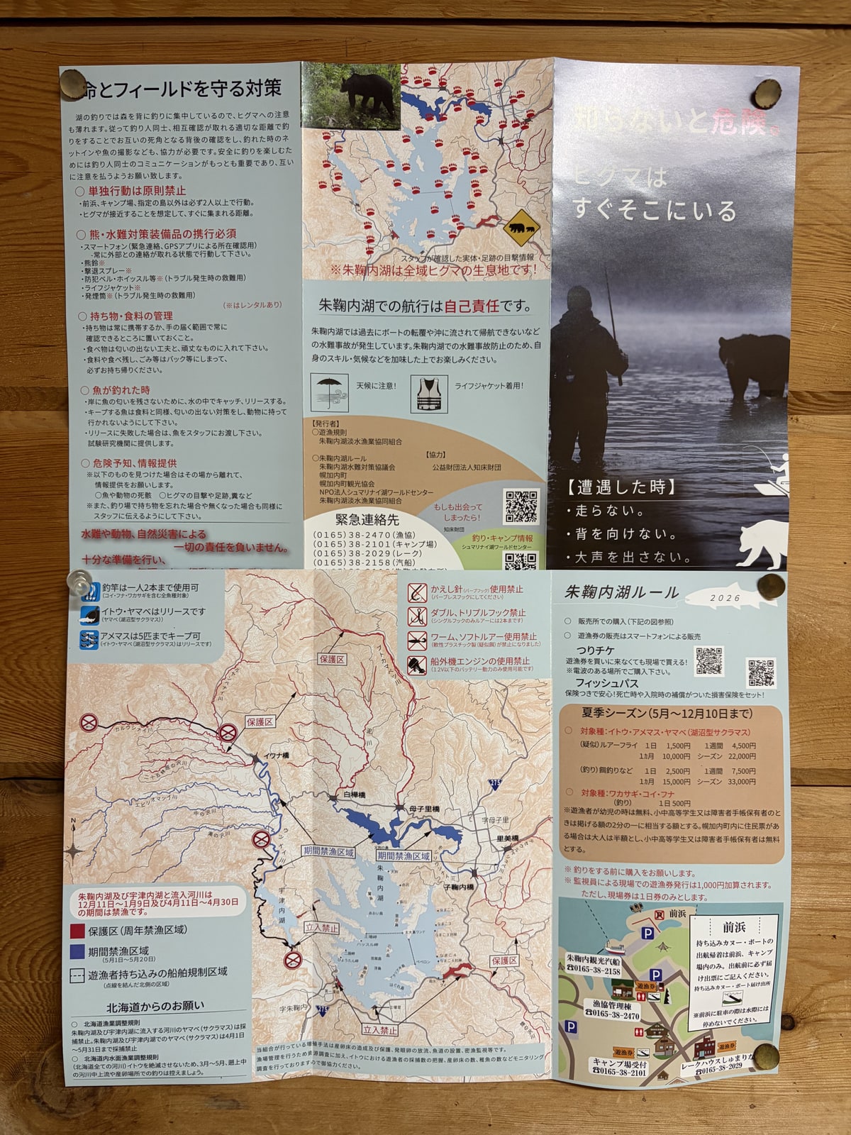 折り畳まれた案内を開いて持っている。湖の地図と、釣りの決まりが刷ってある。